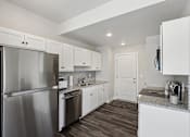 Thumbnail 13 of 16 - A kitchen with white cabinets and a stainless steel refrigerator.
