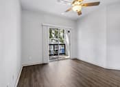 Thumbnail 10 of 61 - A room with a ceiling fan and sliding glass doors leading to a balcony.