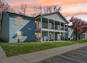 Thumbnail 17 of 35 - 1-Bedroom Apartments in Indianapolis, IN - The Jameson - Apartment Exterior Showing the Two-Story Apartment Building with Light Blue Siding, Balconies, Windows, and Sliding Glass Doors.