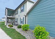 Thumbnail 7 of 35 - the front of a blue house with a sidewalk and green plants