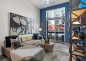 Thumbnail 81 of 95 - Germantown, Nashville, TN,
Apartments Near Nissan Stadium
- Peyton Stakes - Living Room
with Hardwood-Inspired Flooring,
Area Rug, Blue Accent Wall, Grey
Sectional Couch, Round Coffee
Table, Display Shelves, and
Sliding Glass Door with Access to
Pool Area.