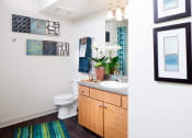 Thumbnail 20 of 25 - Ardenne Apartments Bathroom with light brown vanity, grey countertop, white sink and green and blue striped rug