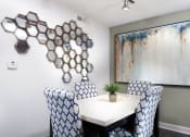 Thumbnail 18 of 25 - Ardenne Apartments Dining room with white table, blue and white chairs, grey walls and mirror art