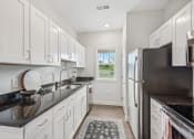 Thumbnail 6 of 36 - a white kitchen with white cabinets and black counter tops