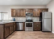 Thumbnail 7 of 11 - Senior Apartments Near Belton, MO for Rent - Traditions Villas 55+ - Kitchen with a High Ceiling, Vinyl Plank Flooring, Custom Cabinetry, Granite Countertops, and Stainless Steel Appliances.