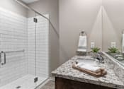 Thumbnail 9 of 11 - A bathroom with a marble counter top and a walk in shower.