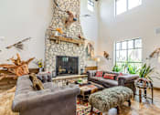 Thumbnail 23 of 30 - A living room with a stone fireplace and a grey couch.