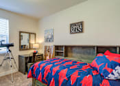 Thumbnail 9 of 30 - A bedroom with a bed covered in a blue and red fish print bedspread.