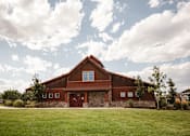 Thumbnail 28 of 30 - A barn with a red roof and a stone foundation.