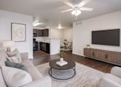 Thumbnail 1 of 23 - A living room with a grey couch, a coffee table, and a flat screen TV mounted on the wall.
