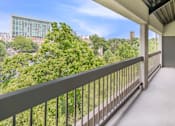 Thumbnail 27 of 27 - A balcony with a metal railing overlooks a cityscape with buildings and trees.