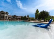 Thumbnail 15 of 48 - a large swimming pool with a blue chair in front of a building