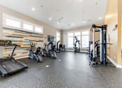 Thumbnail 18 of 22 - A spacious gym with treadmills, elliptical machines, and other exercise equipment.