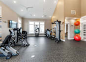 Thumbnail 17 of 22 - A gym with a variety of equipment including treadmills, elliptical machines, and a television.