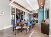 Thumbnail 15 of 22 - Shawnee, KS Apartments Near Kansas Speedway - Bonavia Luxury Apartments - Clubhouse Dining Room with Long Table, Chairs, Storage Cabinets, and Wall-Mounted TV.