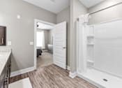 Thumbnail 7 of 22 - A white bathroom with a walk-in shower and a bedroom visible through the door.