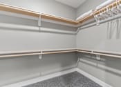 Thumbnail 9 of 22 - 1 Bedroom Luxury Apartments in Shawnee, KS - Bonavia Luxury Apartments - Spacious Closet with Carpeting, Hanging Racks, and Generous Shelf Space.