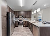 Thumbnail 3 of 22 - A modern kitchen with dark wood cabinets and stainless steel appliances.