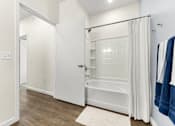 Thumbnail 22 of 47 - A white bathroom with a white tub and a white door.