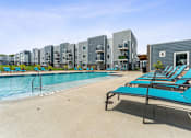 Thumbnail 37 of 47 - A pool with sun loungers and apartment buildings in the background.