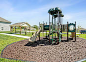 Thumbnail 15 of 16 - Three Bedroom Townhomes In Blue Springs, MO - Chapman Ridge Townhomes - A Playground Includes Multiple Slides, Soft Mulch Ground, Picnic Tables, Sidewalk Paths, And Green Lawn.