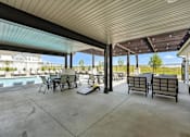 Thumbnail 19 of 36 - A patio with a table and chairs is covered by a roof.