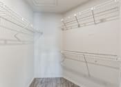 Thumbnail 16 of 22 - A white walk in closet with shelves and a wooden floor.