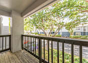 Thumbnail 19 of 22 - A balcony with a black railing and a view of a tree and a building.
