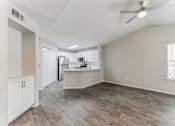 Thumbnail 9 of 22 - A spacious kitchen and living room with wood flooring and white walls.