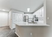 Thumbnail 12 of 22 - A kitchen with white cabinets and a white countertop.