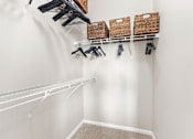 Thumbnail 6 of 71 - A white closet with clothes hanging and baskets on the shelf.