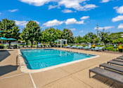 Thumbnail 16 of 30 - A large outdoor swimming pool surrounded by sun loungers and trees.