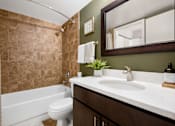 Thumbnail 8 of 30 - A bathroom with a white tub, sink, and toilet.
