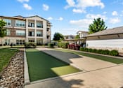 Thumbnail 46 of 47 - Apartment complex with a green lawn and a small putting green.