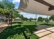 Thumbnail 40 of 47 - A park with a grassy area and a shaded walkway.