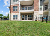 Thumbnail 16 of 47 - A large grassy area in front of a two-story apartment building.