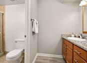 Thumbnail 24 of 30 - A bathroom with a toilet, sink, and mirror.