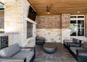 Thumbnail 36 of 47 - A modern outdoor seating area with a stone wall and wooden ceiling.