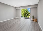 Thumbnail 22 of 30 - A room with a sliding glass door leading to a green outdoor area.