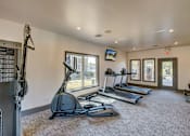 Thumbnail 22 of 26 - A gym with treadmills, elliptical machines, and a television.