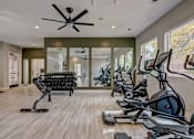 Thumbnail 9 of 40 - a gym with cardio machines and a ceiling fan