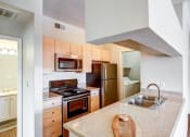Thumbnail 19 of 32 - Apartments In Aurora, CO - Sonoma Resort At Saddle Rock - Kitchen With Granite-Style Countertops, Wood-Style Flooring, Light Cabinets, And Stainless-Steel Appliances.