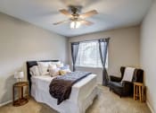 Thumbnail 20 of 32 - One, Two, And Three-Bedroom Apartments In Aurora, CO - Sonoma Resort At Saddle Rock - Bedroom With Bed, Chair, Nightstand, Lamp, Ceiling Fan, And Window.