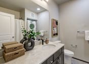 Thumbnail 7 of 25 - A bathroom with a white toilet, a sink, and a mirror.