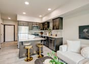 Thumbnail 2 of 25 - A modern kitchen with a white couch and bar stools.
