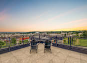 Thumbnail 11 of 25 - Two chairs are placed on a balcony overlooking a cityscape.
