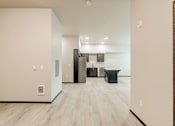 Thumbnail 23 of 25 - A kitchen area with a refrigerator, cabinets, and a countertop.