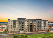 Thumbnail 25 of 25 - A modern apartment building with a green lawn in front.