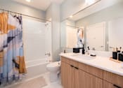 Thumbnail 12 of 43 - A bathroom with a toilet, sink, and shower curtain.