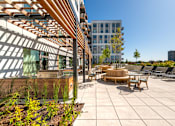 Thumbnail 18 of 43 - A modern outdoor seating area with wooden furniture and a wooden pergola.